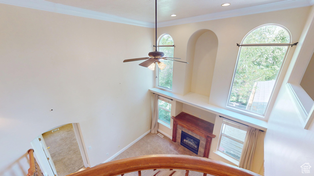 Unfurnished living room with a ceiling fan, a glass covered fireplace, healthy amount of natural light, crown molding, and recessed lighting