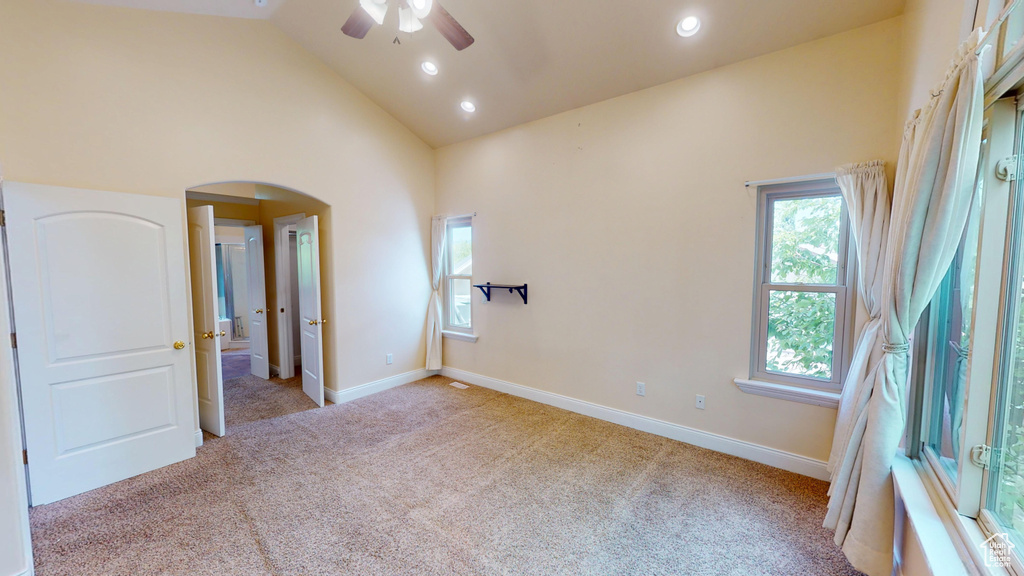 Spare room with ceiling fan, light carpet, arched walkways, recessed lighting, and high vaulted ceiling