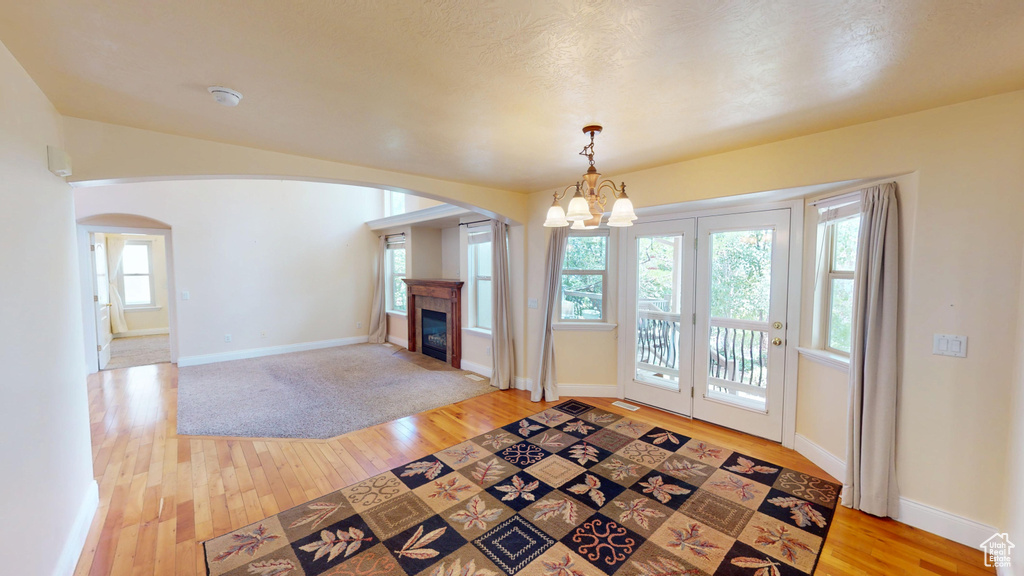 Unfurnished living room featuring arched walkways, a glass covered fireplace, and light wood-type flooring