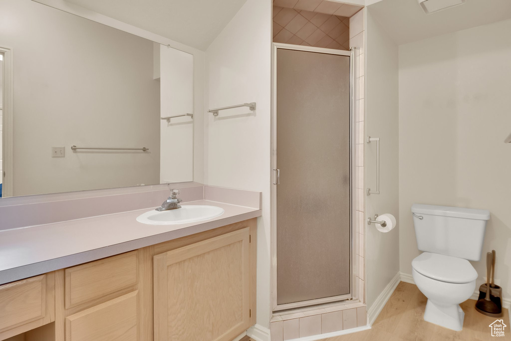 Full bath featuring toilet, vanity, a shower stall, baseboards, and wood finished floors