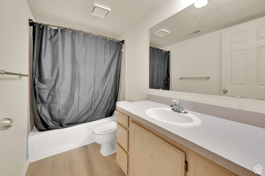 Full bathroom with wood finished floors, vanity, toilet, and shower / bathtub combination with curtain