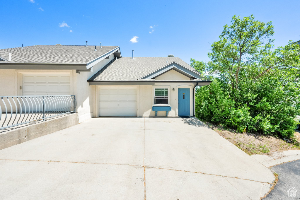 Ranch-style home featuring stucco siding, concrete driveway, an attached garage, and a shingled roof