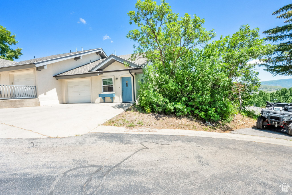 View of front facade featuring stucco siding, a garage, and driveway
