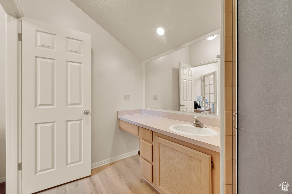 Bathroom featuring vaulted ceiling, vanity, wood finished floors, and baseboards