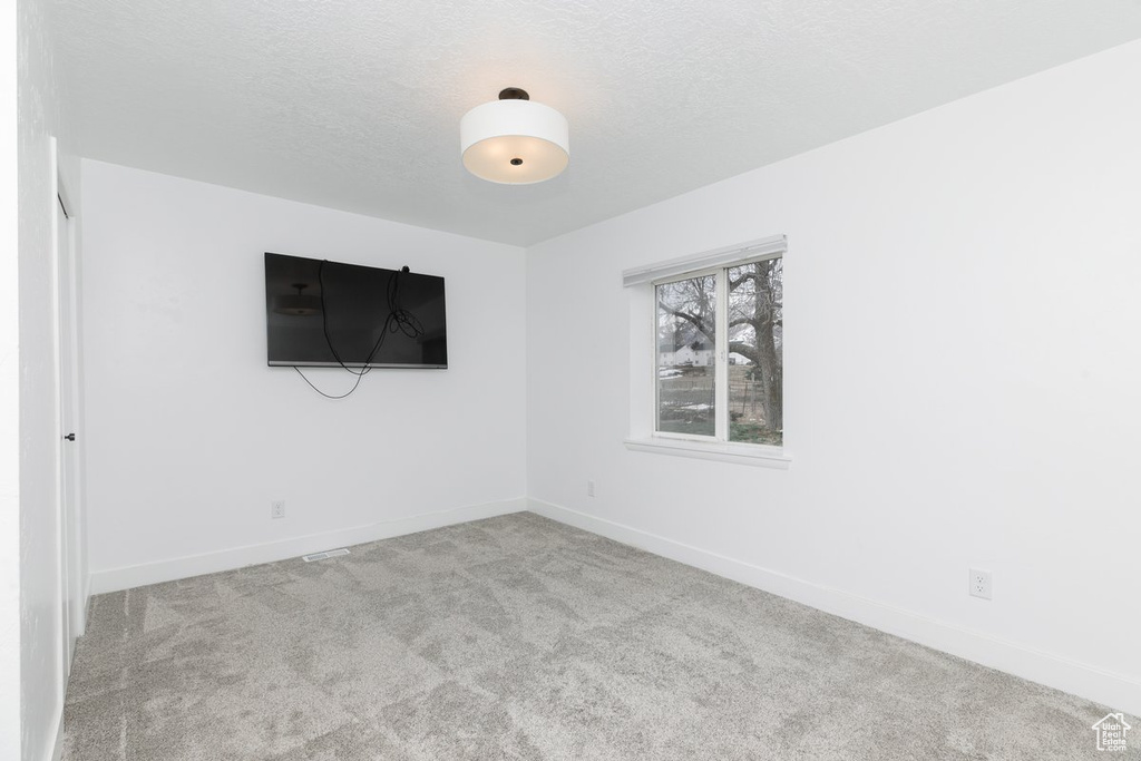 Empty room featuring baseboards, a textured ceiling, and carpet