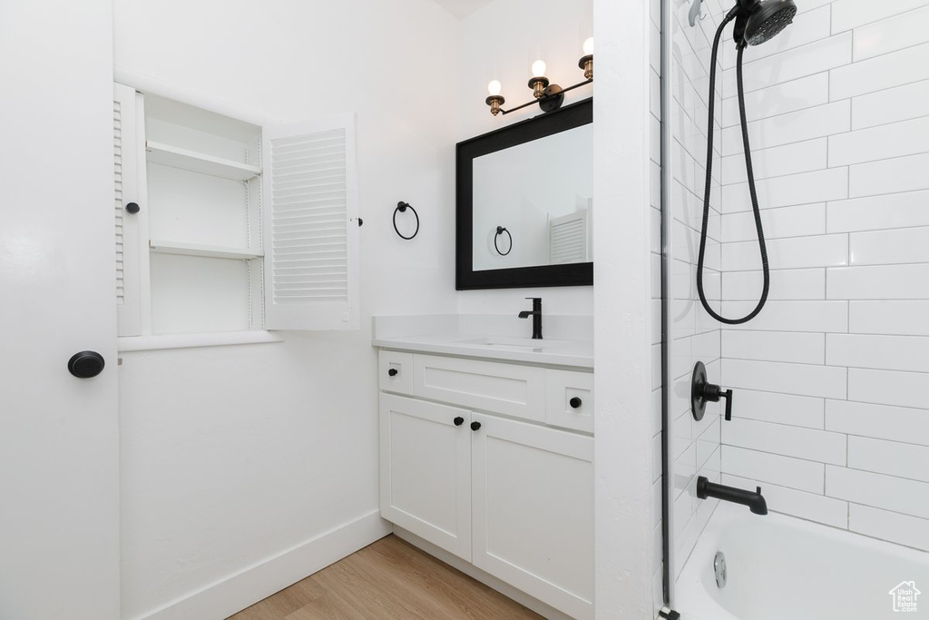Bathroom with baseboards, bathtub / shower combination, vanity, and wood finished floors