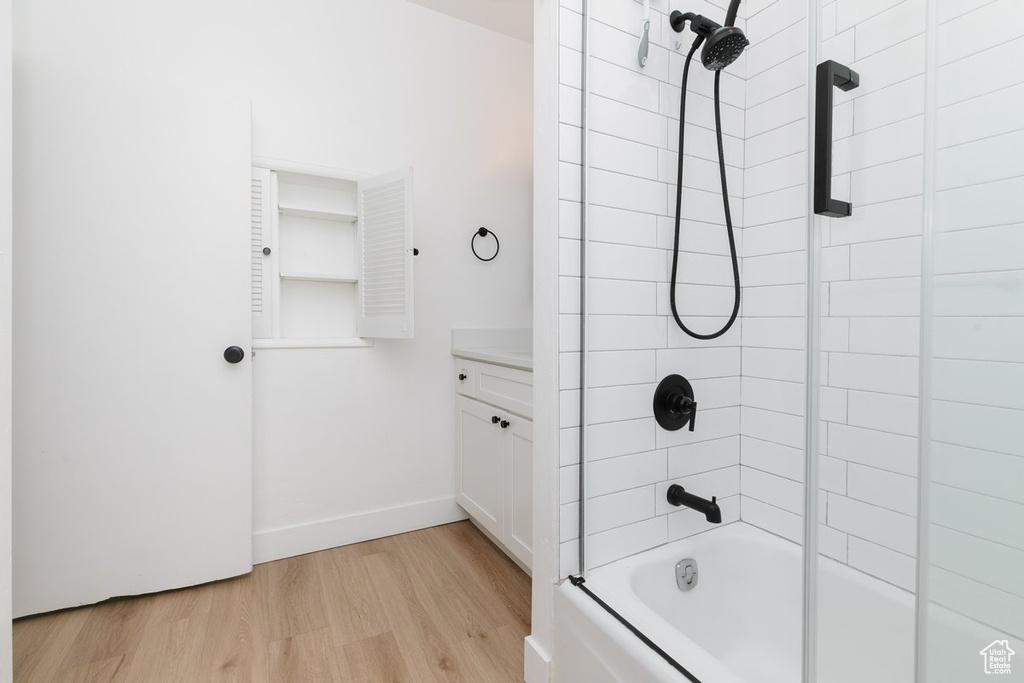 Bathroom featuring bathtub / shower combination, wood finished floors, and baseboards