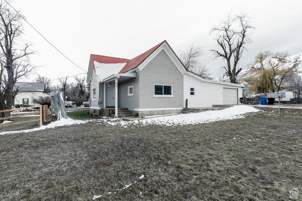 View of home's exterior featuring brick siding, an attached garage, fence, and metal roof