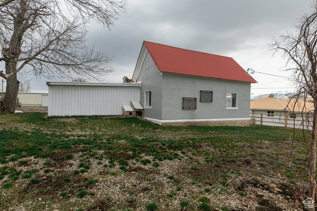 Exterior space with brick siding, a yard, and metal roof