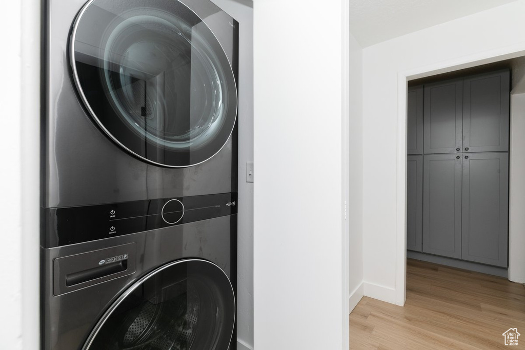 Laundry area featuring baseboards, light wood-style floors, and stacked washer / drying machine
