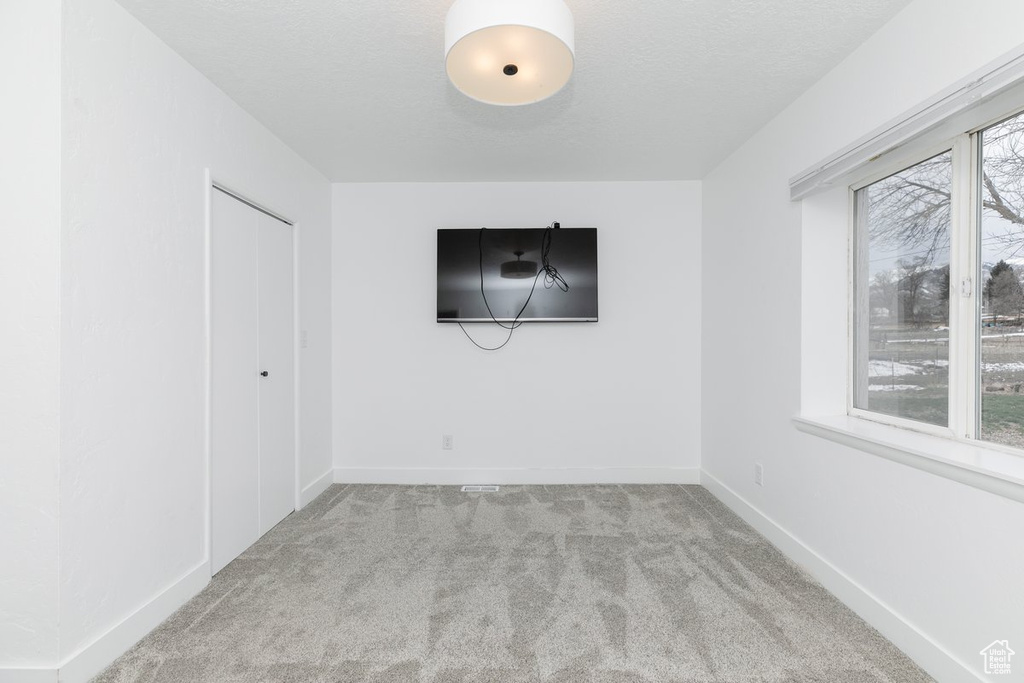 Unfurnished room featuring baseboards, carpet flooring, and a textured ceiling