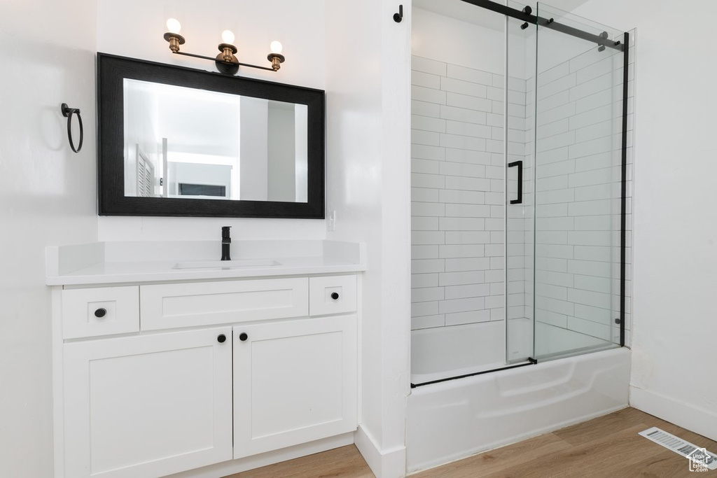 Full bath featuring visible vents, shower / bath combination with glass door, vanity, and wood finished floors
