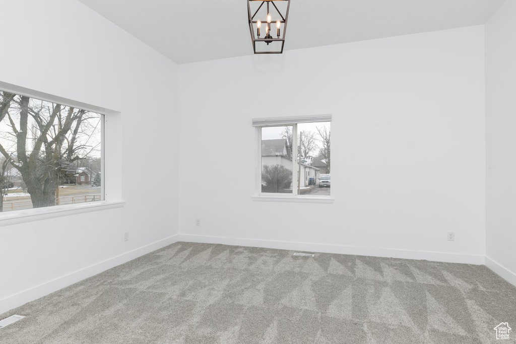 Unfurnished room with carpet flooring, an inviting chandelier, baseboards, and visible vents