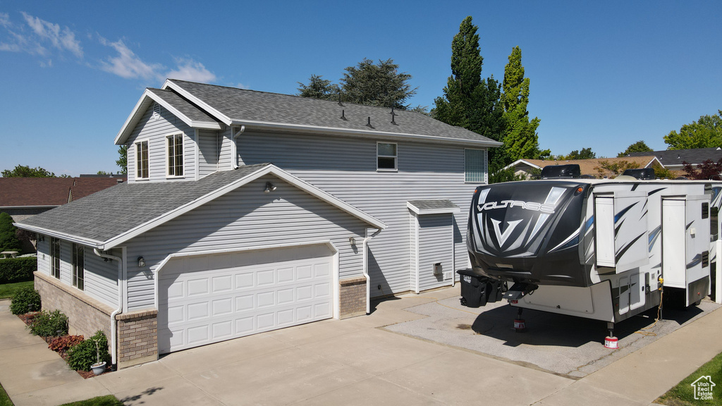 View of front of property featuring roof with shingles, driveway, and a garage