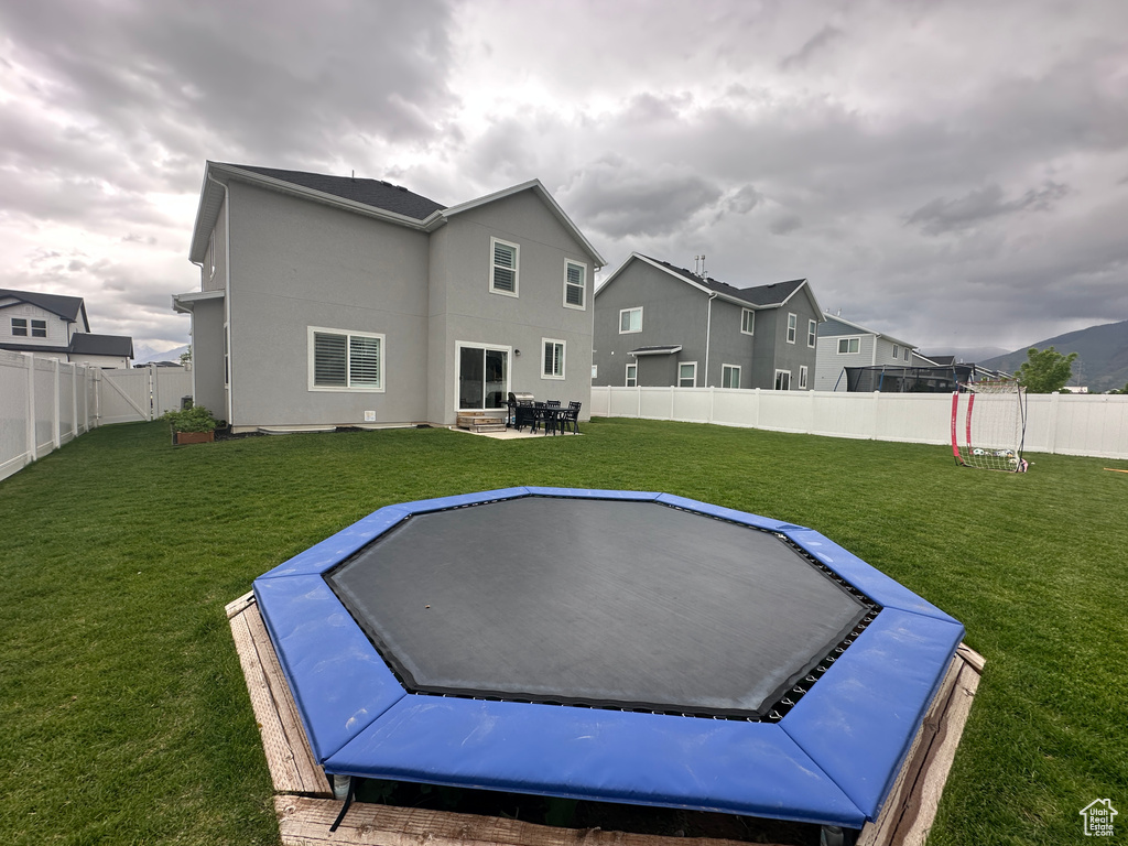 Rear view of house featuring a trampoline, stucco siding, and a patio