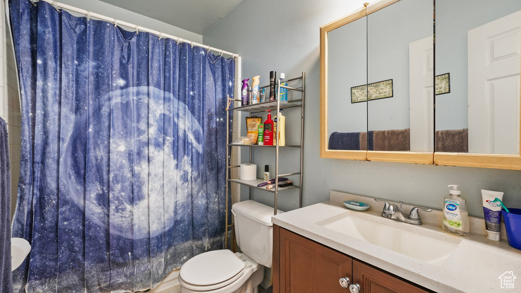Bathroom featuring toilet, a shower with shower curtain, and vanity