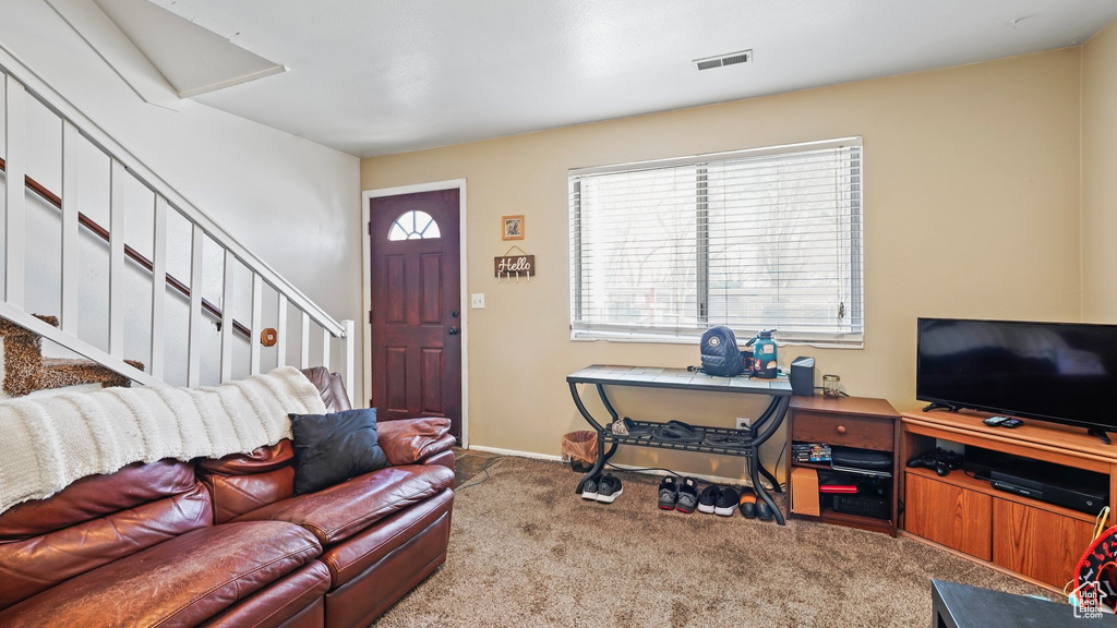 Living room with stairs, visible vents, carpet floors, and baseboards