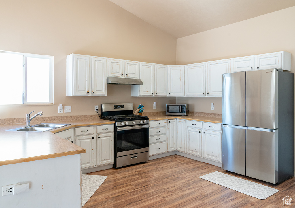 Kitchen with under cabinet range hood, white cabinetry, a sink, and stainless steel appliances
