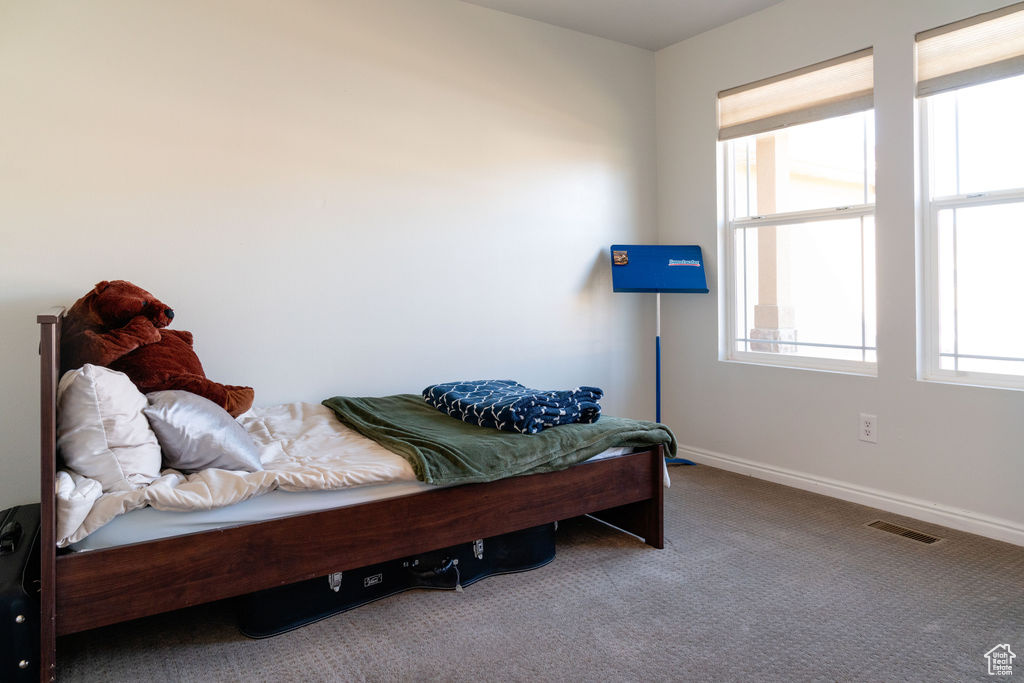 Carpeted bedroom featuring baseboards and visible vents