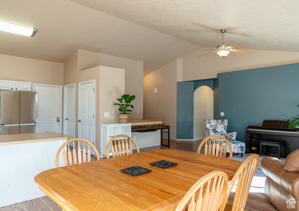 Dining room featuring baseboards, lofted ceiling, light wood-style floors, and ceiling fan
