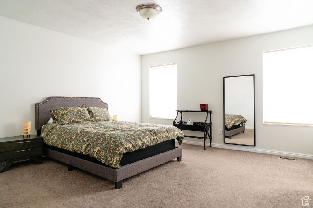 Carpeted bedroom featuring baseboards and visible vents