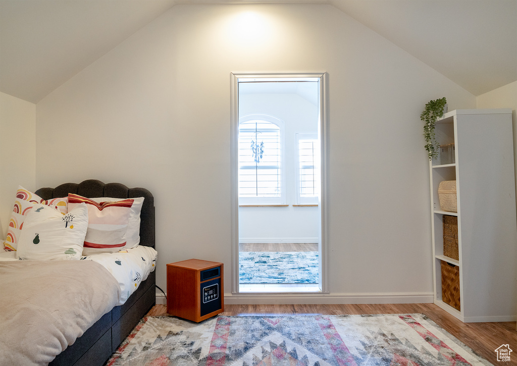 Bedroom featuring baseboards, vaulted ceiling, and wood finished floors