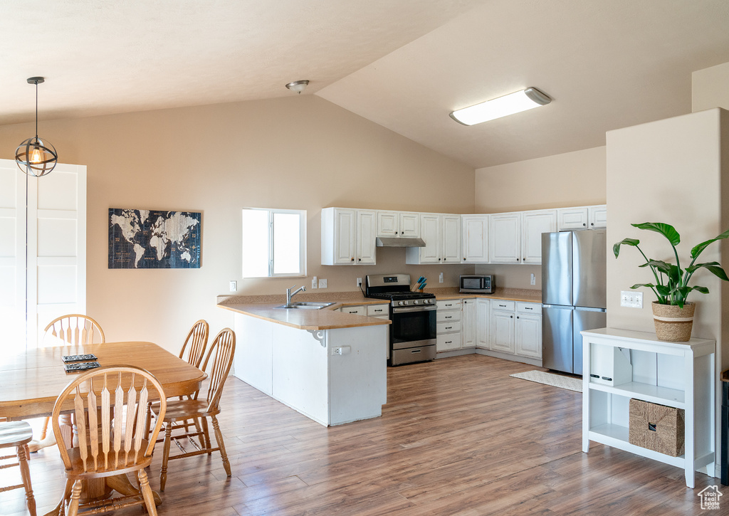 Kitchen featuring under cabinet range hood, white cabinets, a peninsula, and appliances with stainless steel finishes