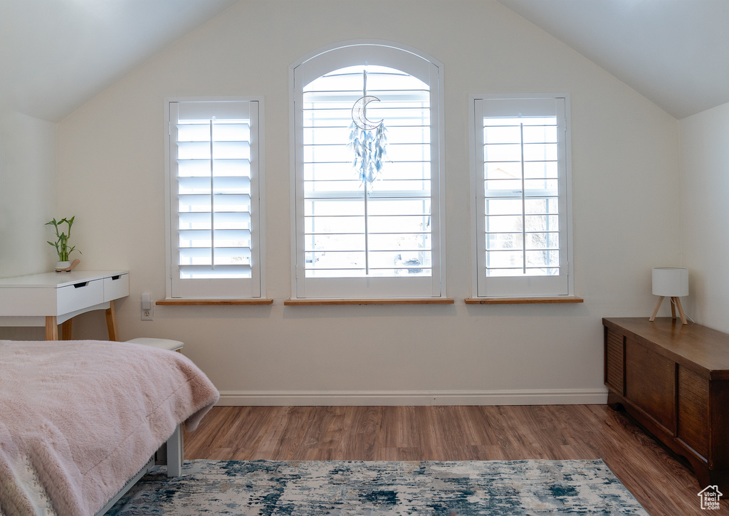 Bedroom with baseboards, vaulted ceiling, and wood finished floors
