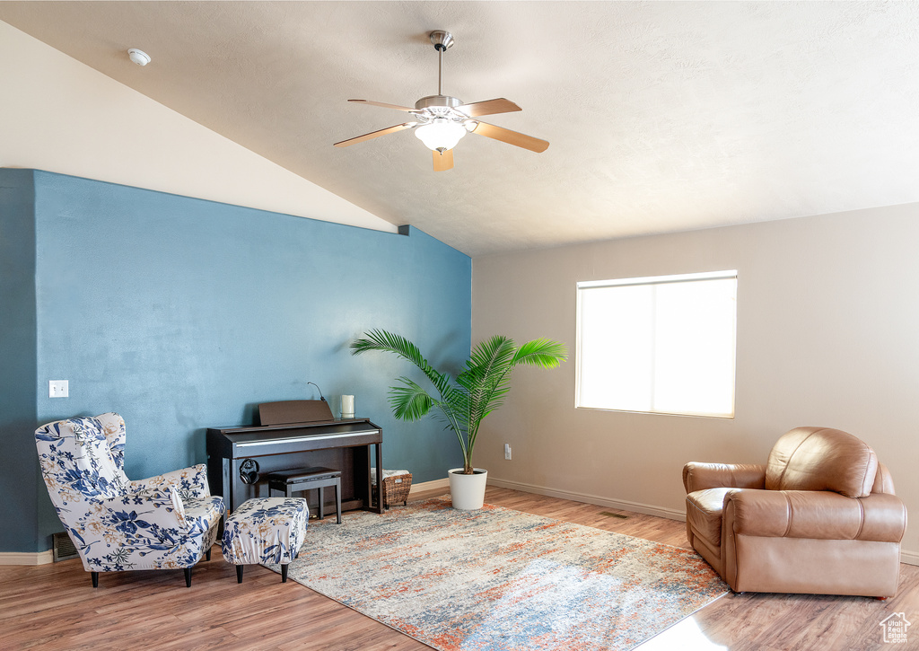 Living area with baseboards, lofted ceiling, ceiling fan, and wood finished floors