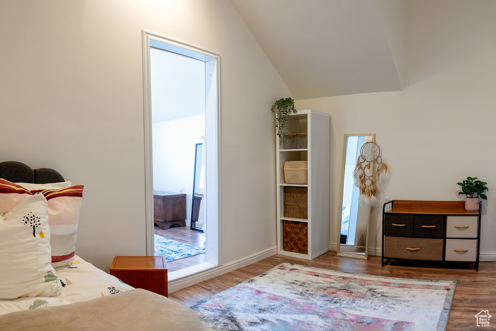 Bedroom with baseboards, lofted ceiling, and wood finished floors