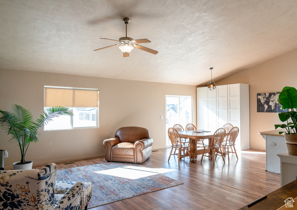 Living area with plenty of natural light, lofted ceiling, wood finished floors, and ceiling fan