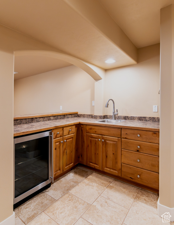 Kitchen with a sink, wine cooler, and brown cabinets