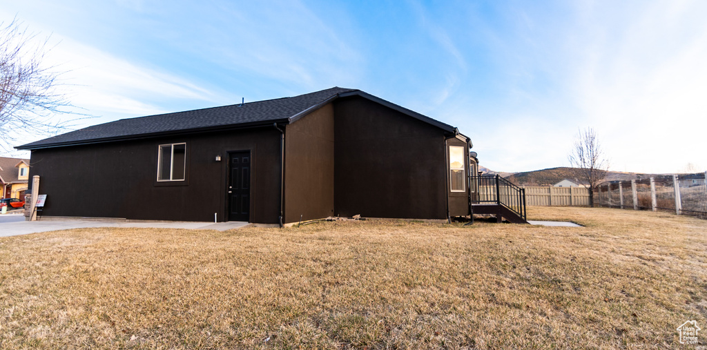 View of side of home with a lawn and fence