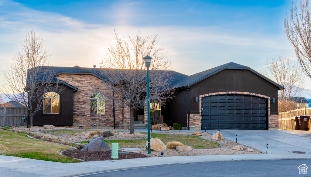 Single story home with stone siding, an attached garage, fence, and concrete driveway