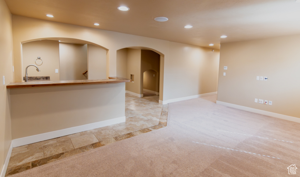 Interior space with light carpet, baseboards, arched walkways, and recessed lighting