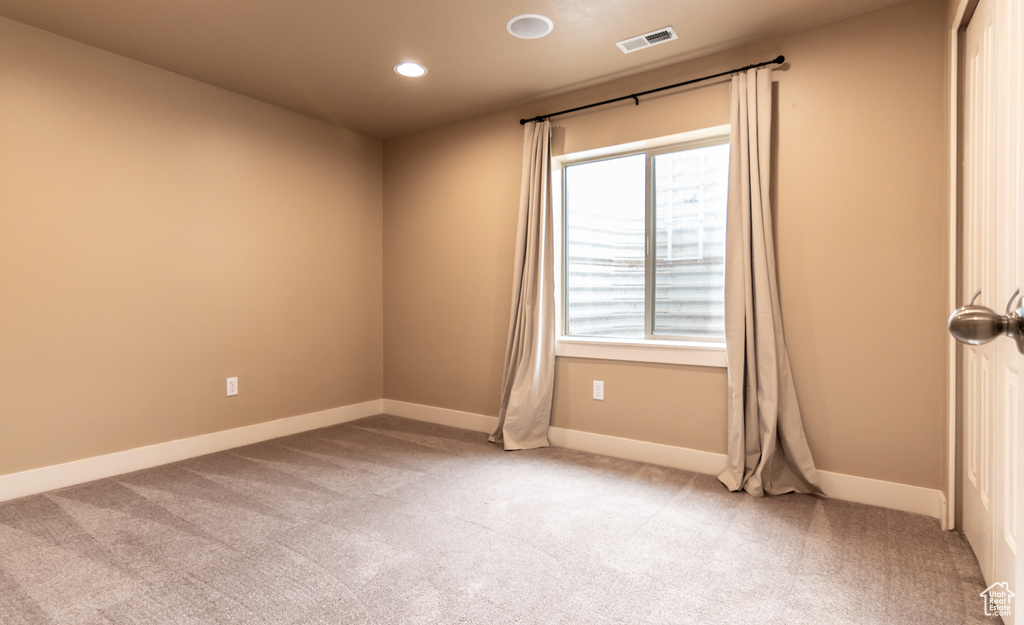 Empty room with baseboards, visible vents, recessed lighting, and light colored carpet