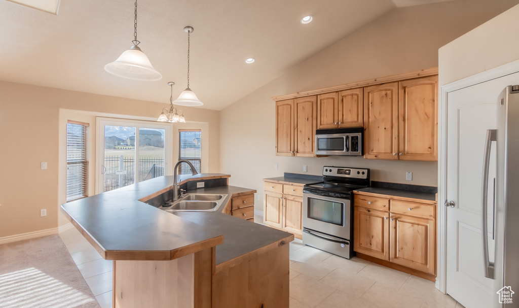Kitchen with a kitchen island with sink, dark countertops, a sink, and stainless steel appliances