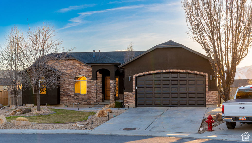 View of front of home featuring stone siding, driveway, and a garage