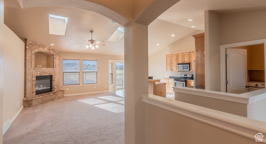 Living room with vaulted ceiling, light colored carpet, baseboards, a ceiling fan, and a fireplace