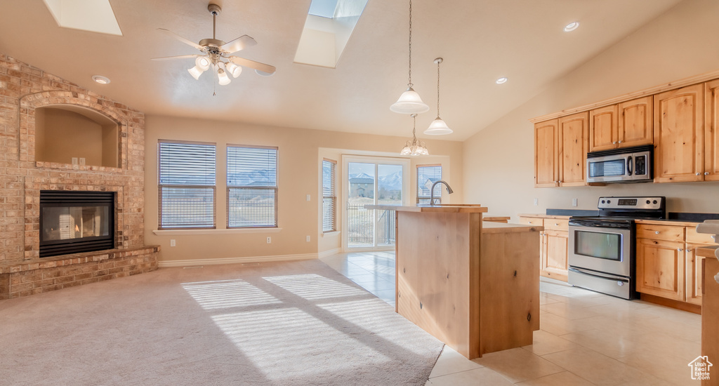 Kitchen featuring light brown cabinets, a kitchen island with sink, stainless steel appliances, and a skylight