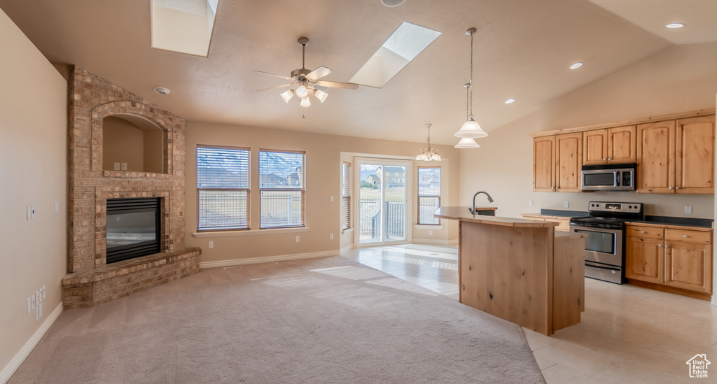 Kitchen featuring a skylight, stainless steel appliances, light brown cabinets, open floor plan, and light colored carpet