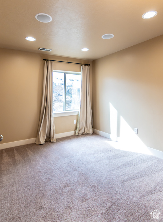 Carpeted empty room featuring baseboards, visible vents, and recessed lighting