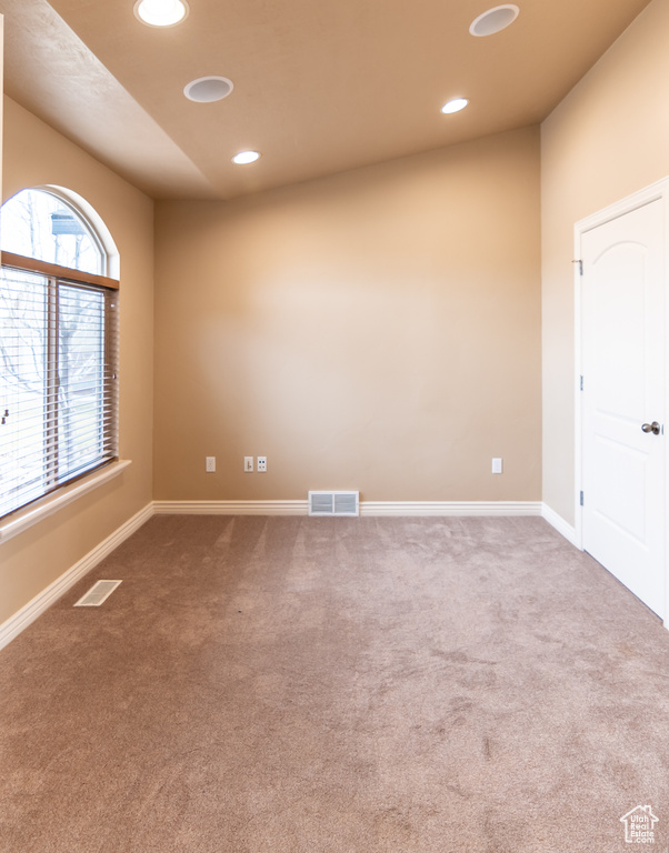 Empty room featuring carpet flooring, visible vents, and recessed lighting
