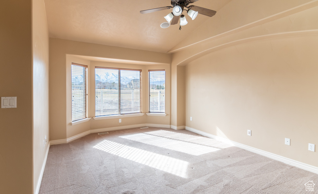 Carpeted spare room with baseboards, lofted ceiling, and ceiling fan
