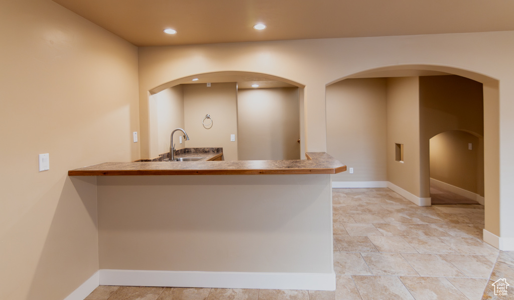 Kitchen with baseboards, recessed lighting, arched walkways, and a sink