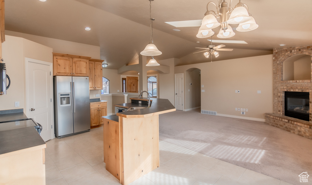 Kitchen with a sink, appliances with stainless steel finishes, open floor plan, ceiling fan with notable chandelier, and arched walkways