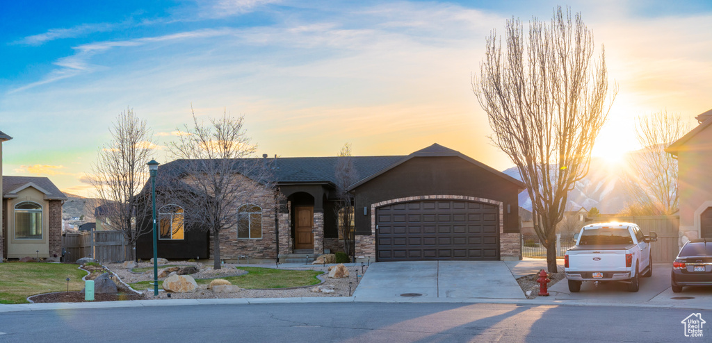 View of front of home with driveway, an attached garage, and stone siding