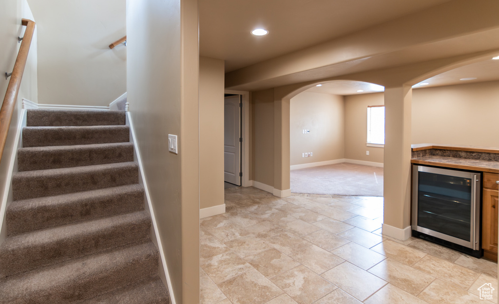Stairs featuring baseboards, wine cooler, recessed lighting, bar, and arched walkways