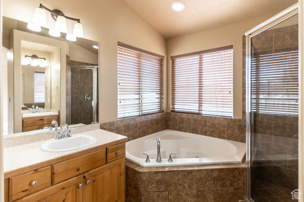 Full bath featuring vanity, lofted ceiling, a garden tub, and a shower stall