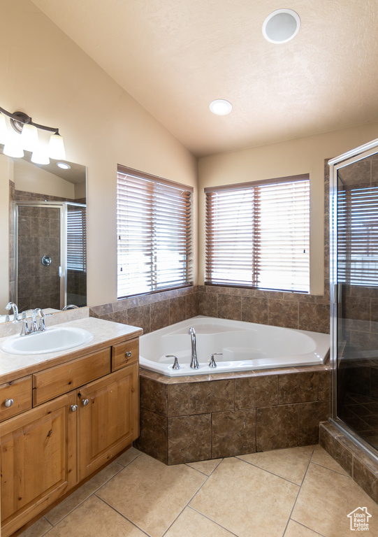 Bathroom with a stall shower, tile patterned floors, vanity, a garden tub, and lofted ceiling
